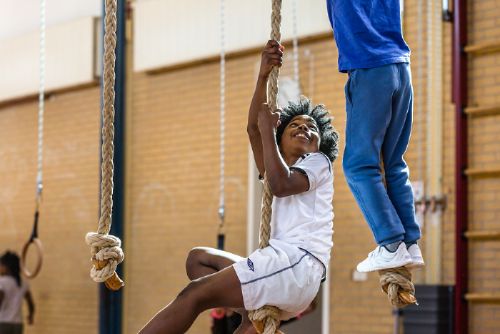 Boy climbing rope in sports hall