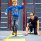 Jumping child in gym of school under supervision of teacher/researcher